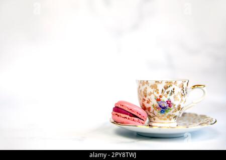 Traditioneller englischer Tee, Nachmittagstee mit altem Porzellantee und rosa Makkarone auf weißem Hintergrund, Kopie Space Pastellfarben Makkaron Stockfoto