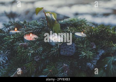 Nahaufnahme Teelichterkerzen in immergrünen Pinienzweigen Konzeptfoto Stockfoto