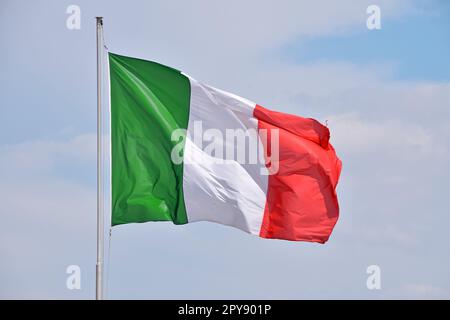 Italienische Flagge, die am wolkenlosen blauen Himmel winkt Stockfoto