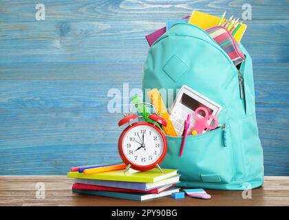 Rucksack mit Schulpapier auf dem Tisch vor blauem Holzhintergrund Stockfoto