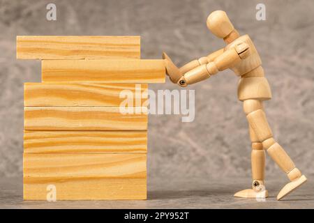 Die hölzerne Dummy baut einen Turm aus Holzblöcken Stockfoto