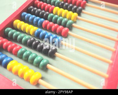 Bildungskonzept - Abakus mit vielen bunten Perlen. Rote, blaue, grüne, schwarze, gelbe Details auf dem Abakus. Mathematische Übungen. Schulprogramm Stockfoto