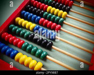 Bildungskonzept - Abakus mit vielen bunten Perlen. Rote, blaue, grüne, schwarze, gelbe Details auf dem Abakus. Mathematische Übungen. Schulprogramm Stockfoto