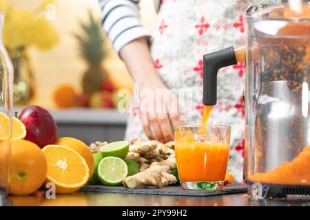 Drücken Sie Karottensaft mit Entsafter gesunde Zitrusfrüchte im Hintergrund. Einnahme Vitamine Entgiftung, gesunde Ernährung und Lebenskonzept. Stockfoto