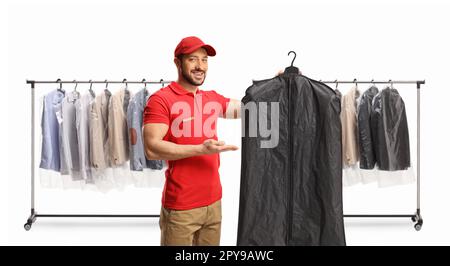 Wäschearbeiter, der Kleidung auf einem Kleiderbügel mit einer Kastenabdeckung vor Kleiderständern hält, isoliert auf weißem Hintergrund Stockfoto