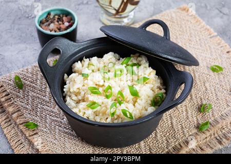 Gedünsteter Reis mit Hühnchen in einem Topf auf grauem Hintergrund Stockfoto