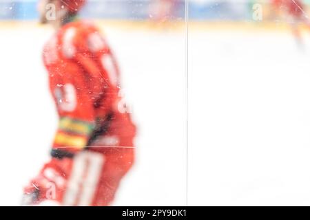 Verschwommene Sicht durch Schutzglas. Hockeyspieler auf der Eisfläche des Stadions Stockfoto