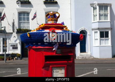 Die Nahaufnahme einer roten Postbox ist mit einer gestrickten königlichen Krone ausgestattet, um König Karls III. Krönung vorzubereiten. Beech Street, Deal, Kent, Großbritannien Stockfoto