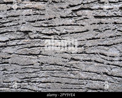 Konsistenz von Beton und Putz an der Wand. Tropfen an die Wand. Wellige Linien im Gips. Konsistenz von Beton und Putz. Graue Farbe Stockfoto