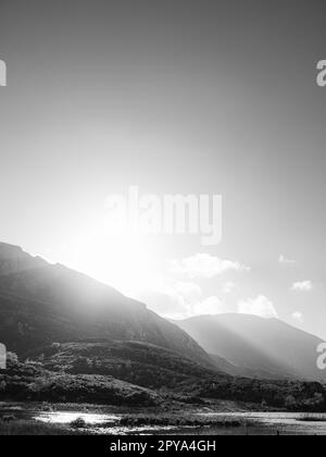 Blick vom Gap of Dunloe in County Kerry, Irland. Die Sonnenstrahlen strömen über die Berge und in das Tal darunter. Stockfoto