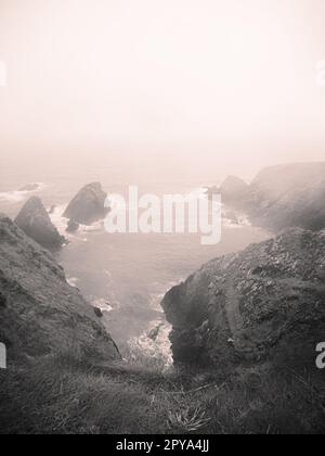 Blick vom Slea Head in County Kerry Island, in der Nähe der Stadt Dingle. Dieses Foto zeigt einen steilen Abstieg auf den Atlantischen Ozean an einem stürmischen, nebligen Tag Stockfoto