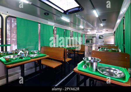 Innenausstattung einer mobilen Kantine für Soldaten, in einem Bus untergebracht: Tische mit Besteck, Mini-Küche. Staroe, Ukraine. Stockfoto