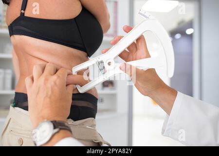 Ernährung speazialistische Ärztin, die Bauchfett an einer Frau misst. Belly Chubby paunchy Sport Erholung Gesundheit verlieren Bauch Fett Konzept. Stockfoto