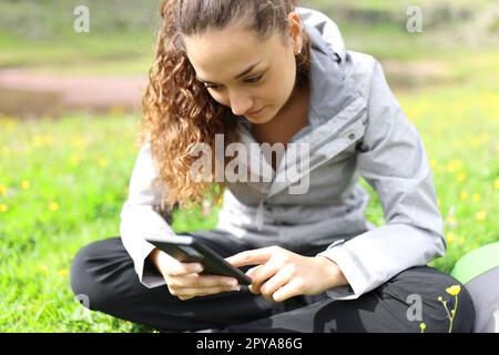 Wanderer, der auf dem Rasen auf dem Handy sitzt Stockfoto