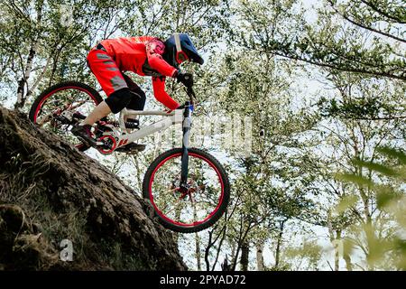 Weibliche Rennradfahrerin, die im Wald ein steiles Abwärtsrennen fährt, Sommer-Mountainbike-Meisterschaft Stockfoto