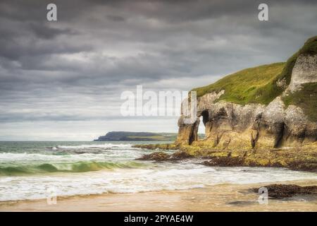 Stürzende Wellen und Kalksteinfelsen am White Rocks Beach, Nordirland Stockfoto