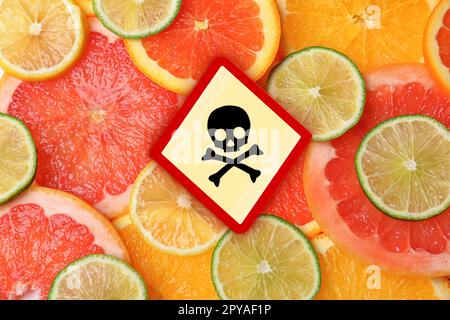 Totenkopf und Kreuzbein-Schild auf verschiedenen frischen Zitrusfrüchten, Draufsicht. Vorsicht - giftig Stockfoto