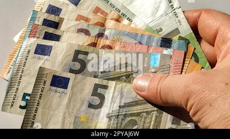Euro-Papiernoten. Europäische Währung auf weißem Hintergrund. Hand und Finger einer älteren Person oder einer Frau mittleren Alters auf Geld. Banknoten der Zentralbank für 5, 10, 20, 50 und 100 Stockfoto