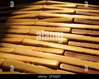 schilf- oder Holzmatte. Der Teppich ist eine Matte unter dem heißen Wasser. Gestrickte Holzstäbe mit abgerundeten Kanten. Nahaufnahme. Gelb, Braun und Beige. Seitenbeleuchtung. Traditionelle Bambuspolsterung Stockfoto