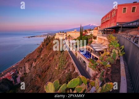 Taormina, Sizilien, Italien. Stadtbild der malerischen Stadt Taormina, Sizilien mit Vulkan Mt. Ätna im Hintergrund bei Sonnenaufgang. Stockfoto