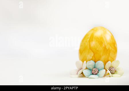 Ostereier in Pastelltönen auf weißem Hintergrund mit Kopierbereich und süßen Frühlingsblumen, Konzept für frohe Osterferien mit Platz für Text. Gelb, rosa und blau Stockfoto