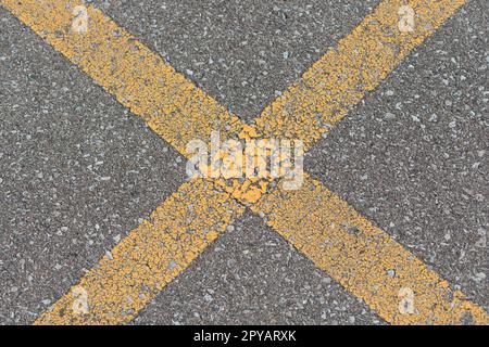 Nahaufnahme des Treffpunkts zwischen zwei Parkplatzlinien auf einer Asphaltfläche, Stockfoto