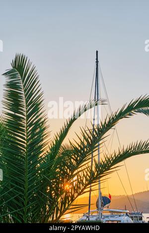 Fethiye, Türkei - 21. Oktober 2022: Yachten liegen in der Bucht vor. Sonnenuntergang in der Bucht von Fethiye, vertikaler Schuss, selektiver Fokus auf die Schiffe. Urlaubsideen Stockfoto