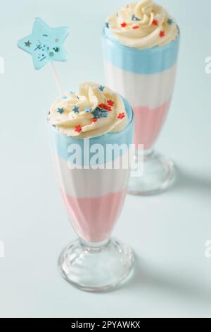 Zwei Patriotische Milchshake oder süßes Dessert für Kinder für den Unabhängigkeitstag auf blauem Hintergrund. Essen für den 4. Juli oder Memorial Day. Stockfoto