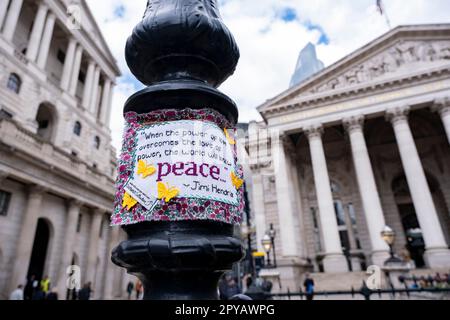 Gesticktes Friedenszitat von Jimi Hendrix, das am 25. April 2023 in London, Großbritannien, an einen Lampenpfahl vor der Bank of England in der City of London genäht wurde. Das Stück stammt vom Handwerkskollektiv. Das Zitat lautet: "Wenn die Macht der Liebe die Liebe der Macht überwindet, wird die Welt Frieden finden." Stockfoto