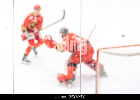 Verschwommene Sicht durch Schutzglas. Hockeyspieler auf der Eisfläche des Stadions Stockfoto