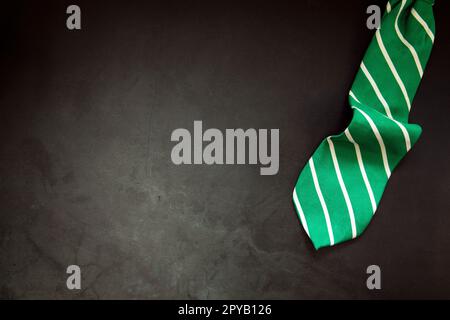 Elegante, grün gestreifte Krawatte auf dunklem Betonhintergrund, Draufsicht, Kopierbereich, Herren, Geschäft, Meeting, Party-Konzept Stockfoto