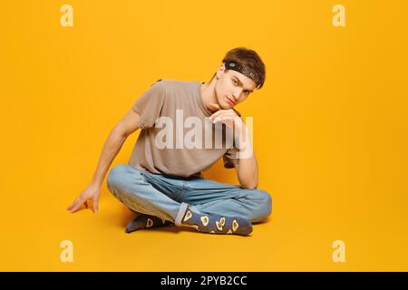 Lässiger junger Erwachsener in einem lebhaften gelben Studio Stockfoto