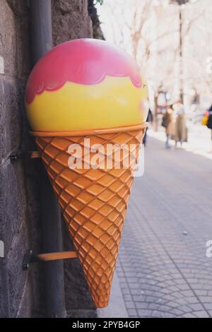Großes Plastikeis-Tüpfelchen-Schild für Café oder Süßwarenladen auf der städtischen Straße - Dessert- und Süßigkeiten-Konzept Stockfoto