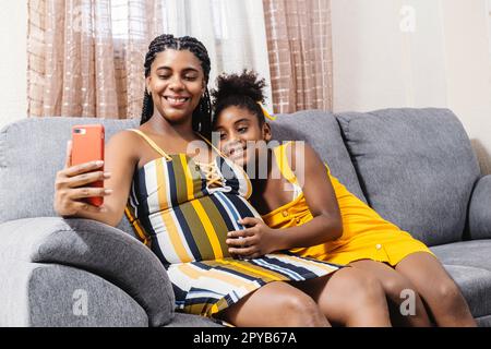 Eine glückliche afroamerikanische Mutter und Tochter, die zu Hause ein Selfie auf der Couch machen Stockfoto