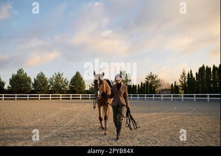 Weibliche Reiterin, die nebeneinander reitet und einen Sattelgurt hält Stockfoto