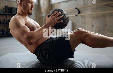 Ein Mann, der Fitnesstraining macht, bauchmuskeltraining mit Medizinball im Fitnessstudio macht Stockfoto