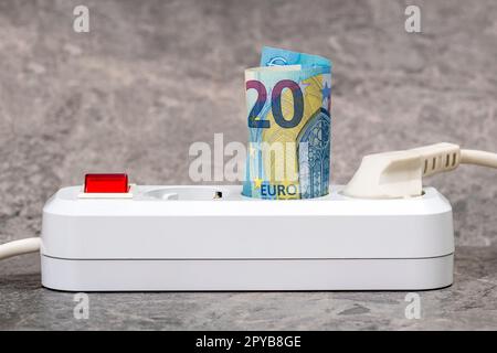 Zwanzig Euro in eine weiße Steckdosenleiste gesteckt Stockfoto