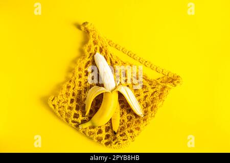 Eine Schnur-Tasche mit Bananen isoliert auf gelbem Hintergrund. Stockfoto