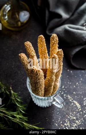 Italienische Grissini-Brotstangen mit Sesamsamen im Becher auf dem Küchentisch. Stockfoto