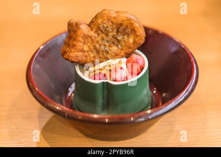 Japanische Fischförmige süße Taiyaki mit roten Bohnen oder Vanillepudding einfügen innerhalb und Erdbeeren auf Vanille Eis in einem Bambus geformte Schale. Stockfoto