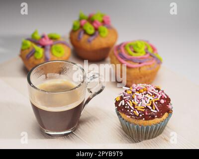 Cupcake mit farbenfroher Dekoration und Kaffee Stockfoto