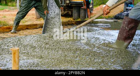 Bauarbeiter gießt nassen Beton auf der Baustelle. Bauarbeiter, der mit Transportbeton aus Zementmischwagen arbeitet. Baukonzessionskonzept. Bauarbeiter gießen Zement. Stockfoto