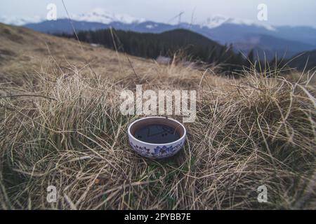 Nahaufnahme des Keramik-Teebechers, der auf getrocknetem Gras steht, Konzeptfoto Stockfoto