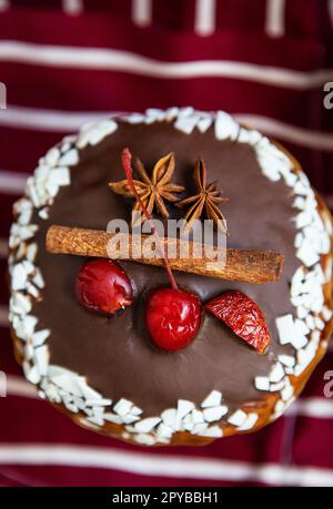 Ein traditioneller paska mit weißer und dunkler Schweizer Schokolade und Kirschen, Zimt und Sternanis steht auf einer Kirschschschürze. Osterferien, Top Aussicht und Nahaufnahme. Stockfoto