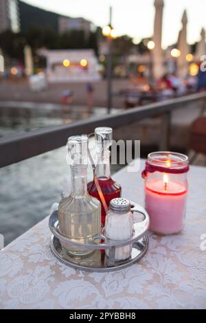 Die Terrasse des Restaurants am Meer, es gibt eine Kerze auf dem Tisch. Vor dem Hintergrund eines wunderschönen Resorts. Romantisches Abendessen am Meer. Stockfoto