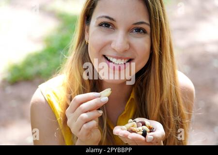 Natürlich gesundes Mädchen, das Nüsse aus der Hand pflückt im Park. Sieht aus wie in der Kamera. Stockfoto