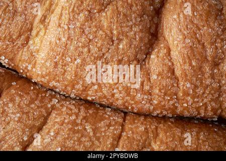 Nahaufnahme der Oberfläche von frisch gebackenem süßzuckerbeschichtetem Brötchen, gestreutem Zucker und Tonung, Vollformatansicht des Lebensmittelhintergrunds Stockfoto