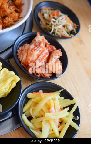 Vertikale Aufnahme koreanischer Speisen in schwarzen Gerichten. Stockfoto