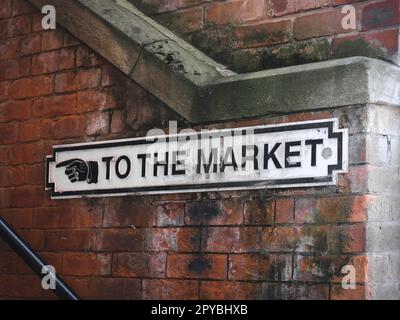 Schild mit der Aufschrift „to the Market“ neben den Stufen zur Market Place Hall, Stockport, UK Stockfoto
