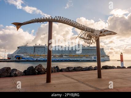 PUERTO DEL ROSARIO, SPANIEN - FEBRUAR 16: (ANMERKUNG: Für dieses Bild wurde ein abgestufter Farbfilter verwendet. Das Bild ist ein digitales Composite mit hohem Dynamikbereich.) Am 16. Februar 2023 in Puerto del Rosario, Spanien, liegt ein Aida-Ozeanliner nahe dem Skelett eines Wals im Hafen. Stockfoto